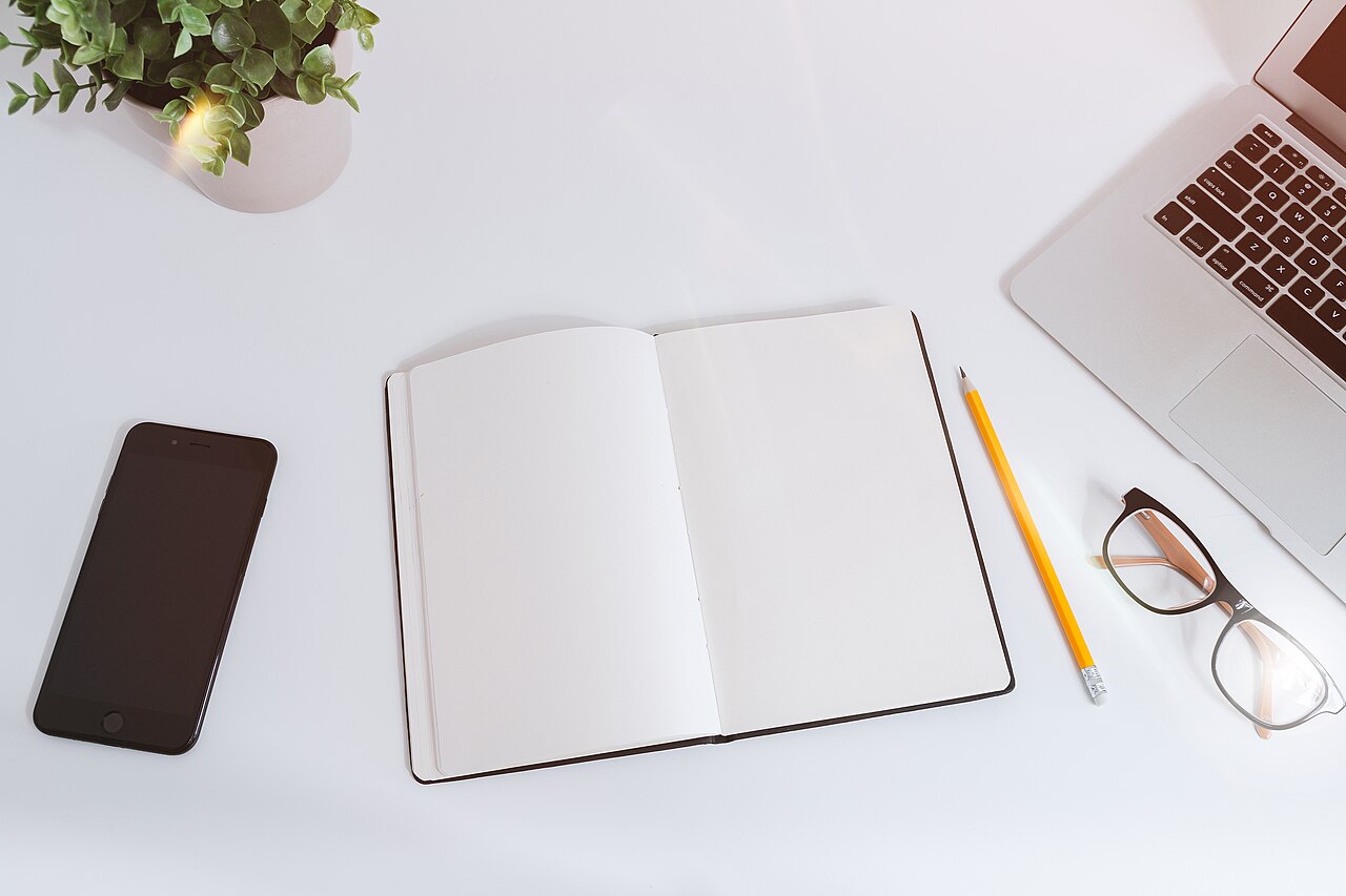 White work table with a laptop, smartphone and notes for everyday tasks